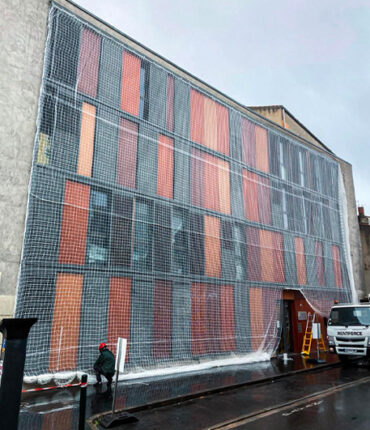 Pose d'un filet de sécurité pour la rénovation d'une façade d'un immeuble au centre ville par Acrobat Travaux, société de rénovation et cordiste sur Vieille Toulouse