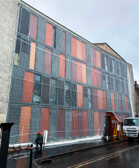 Pose d'un filet de sécurité pour la rénovation d'une façade d'un immeuble au centre ville par Acrobat Travaux, société de rénovation et cordiste sur Vieille Toulouse